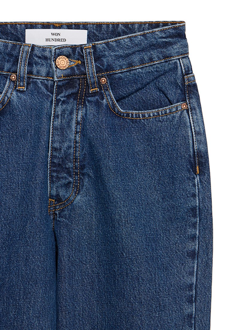 Granatowe dżinsy o średnim stanie, z brązowym zapięciem na guzik i żółtymi przeszyciami. Posiadają kieszenie z przodu oraz metkę.