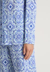 Blue and green patterned pajama set in a floral design, made of fabric with a smooth texture, featuring an elastic waistband and fitted sleeves.
