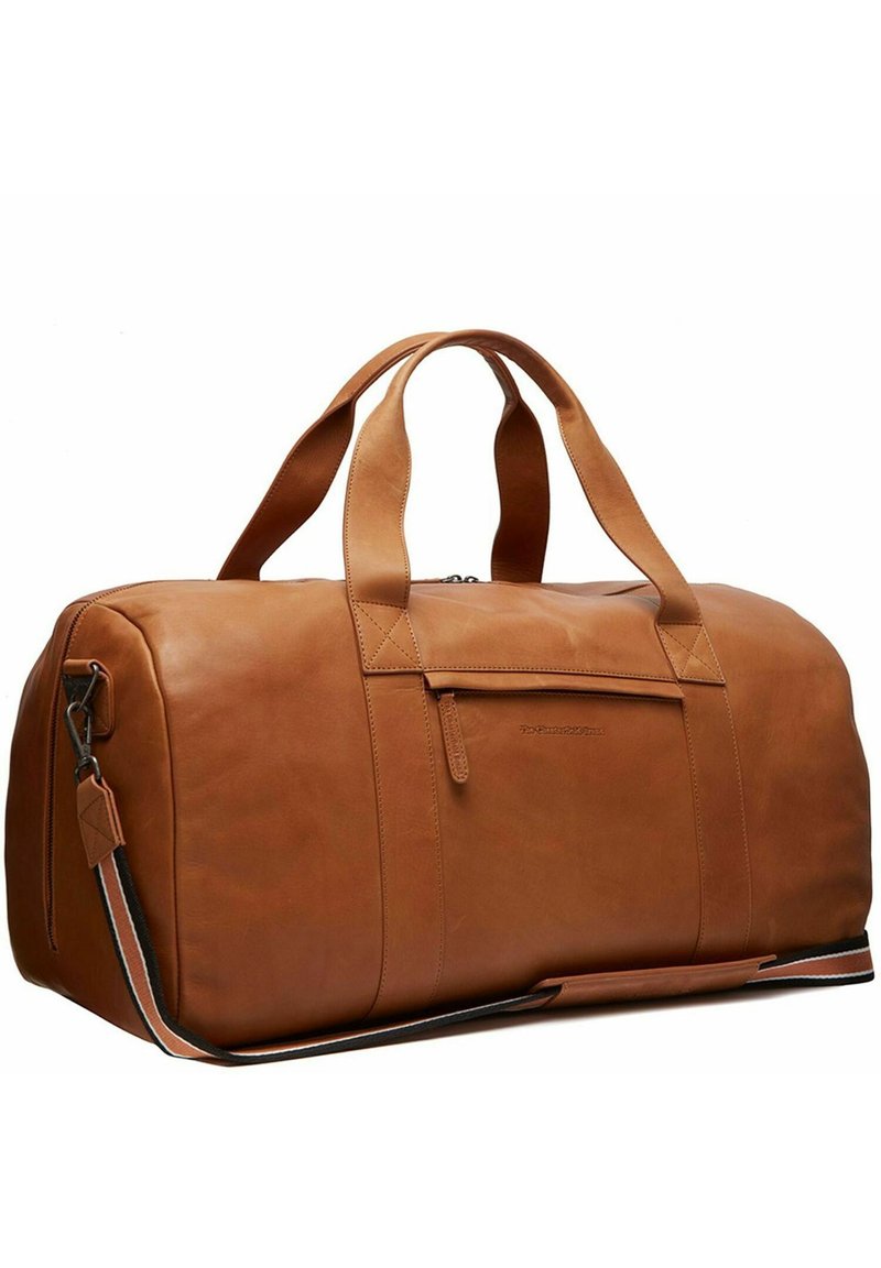 Bolsa de viaje de cuero marrón con textura suave, asas superiores, correa de hombro desmontable y cierre de cremallera con detalle en el bolsillo frontal.