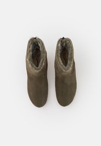 Botas de tobillo de ante verde oliva con forro de piel sintética, punta redonda y cierre lateral con cremallera. Textura suave y diseño minimalista.