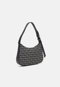 Torebka na ramię o zaokrąglonym kształcie. Tkanina pokryta powtarzającymi się czarnymi literami na beżowym tle, kontrastujący czarny skórzany pasek i wykończenia.