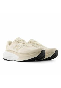 Scarpe da corsa beige con una tomaia testurizzata, dotate di un'intersuola bianca e una suola nera. Presentano un logo "N" grigio chiaro sul lato.