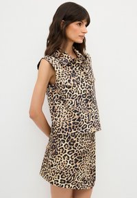 Leopardenmuster ärmelloses Oberteil mit passendem Minirock, in beige und schwarz, strukturiertem Design und goldenen Knopfakzenten.