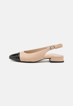 Zapato slingback beige con puntera de charol negro brillante, tacón bajo y acabado de cuero suave. Detalle de correa ajustable en la parte posterior.