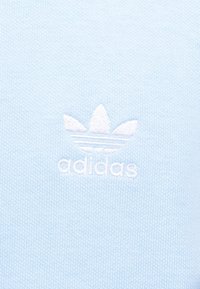 Φωτεινό γαλάζιο πλεκτό ύφασμα με το λευκό λογότυπο Adidas, που περιλαμβάνει το σύμβολο trefoil και το όνομα της μάρκας κεντημένα στο κέντρο.