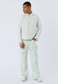 Groen gestreepte, gestructureerde jas met knopen, gecombineerd met bijpassende cargobroek met zijzakken en een relaxte pasvorm.