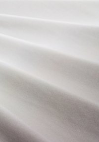 Witte stof met subtiele textuur, met zachte plooien en een gladde glans. Het oppervlak lijkt licht en flexibel.