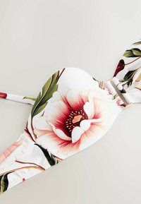 Haut de bikini floral présentant un fond blanc, des fleurs roses et rouges, des feuilles vertes, un tissu lisse avec un centre froncé et des bretelles réglables.