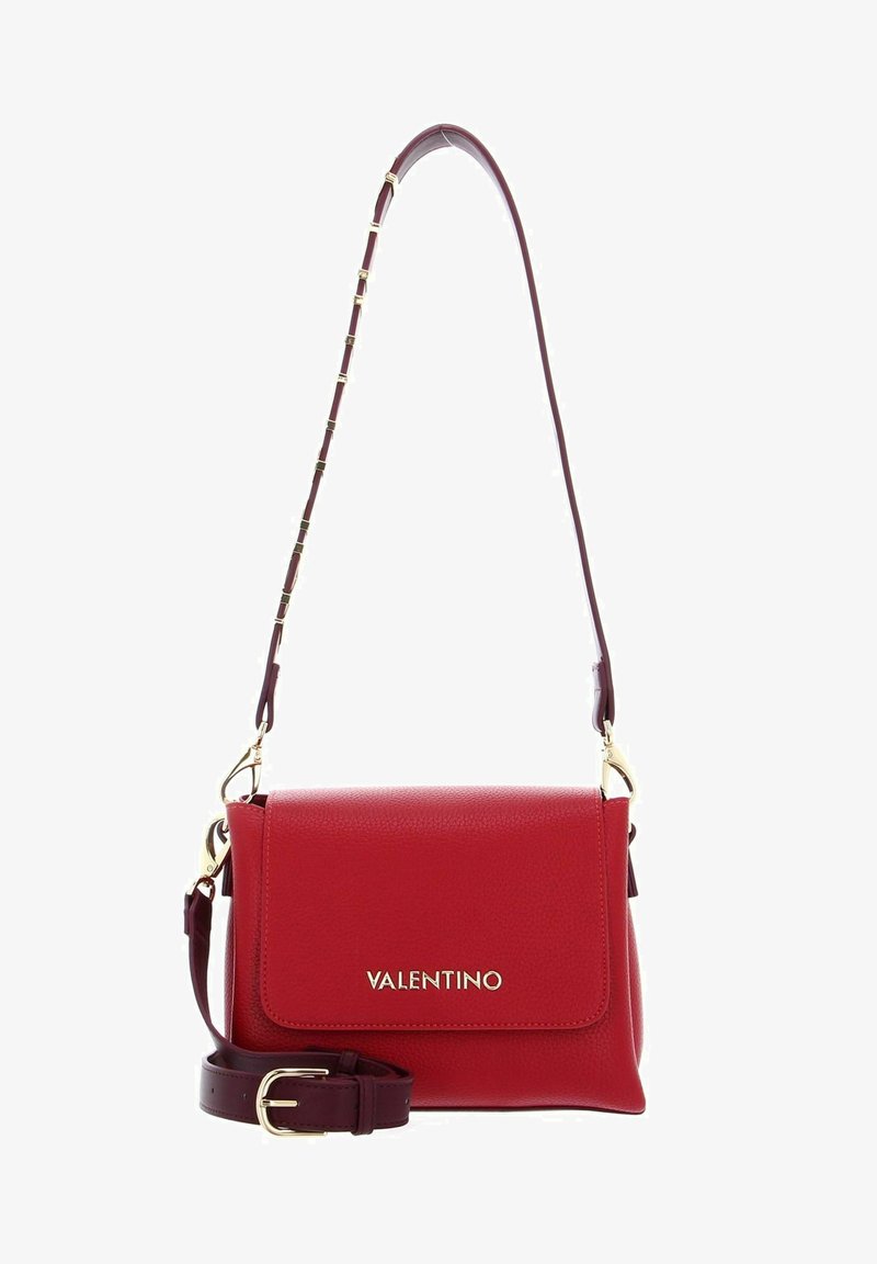 Sac à main en cuir rouge avec une finition texturée, quincaillerie dorée et une bandoulière amovible dotée de petits maillons décoratifs. Le rabat avant présente le logo.