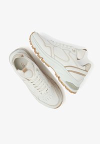 White leather sneakers with a textured design, round toe, lace-up front, and beige accents. Thick, rubber outsole with a slight heel.