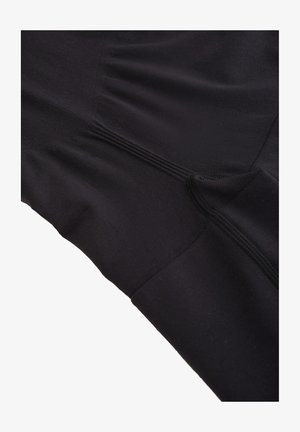 Black athletic top made of smooth fabric, featuring a fitted design, textured seams, and subtle ruching details along the side.