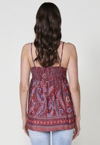 Top senza maniche con motivo paisley rosso, con corpetto arricciato e spalline sottili, caratterizzato da accenti blu e bianchi lungo l'orlo e l'area delle spalle.