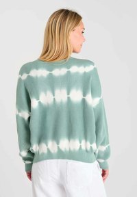 Lichtgroene geribde trui met een wit tie-dye patroon, gekenmerkt door een relaxte pasvorm en lange mouwen, textuurstof en een ronde halslijn.
