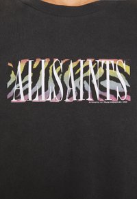 Musta T-paita, jossa on grafiikka sanalla "ALLSAINTS" lihavoidulla valkoisella fontilla monivärisen seeprakuosisin taustan päällä.