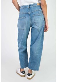 Jeans de mezclilla de color azul claro, de pierna ancha y cintura alta, con dos bolsillos traseros y una etiqueta de cuero marrón en la cinturilla. Ajuste casual y relajado.
