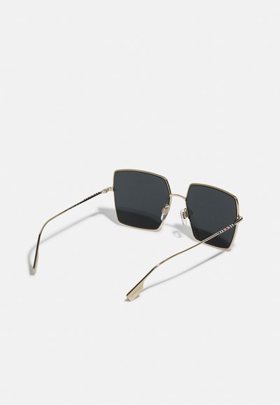 Ochelari de soare pătrați cu lentile întunecate, cadru din metal aurit și brațe decorative cu model. Dispun de pernuțe pentru nas pentru confort și fixare sigură.