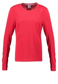Czerwona sportowa koszulka z długim rękawem wykonana z teksturowanej tkaniny, z okrągłym dekoltem i subtelnym logo na górnej lewej stronie.