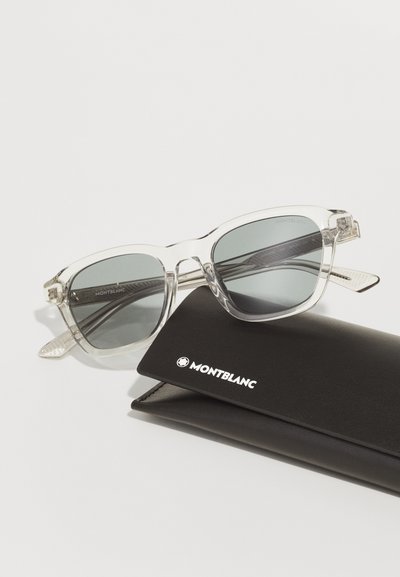 Lunettes de soleil Montblanc avec une monture en acétate transparent et des verres gris, présentées dans un étui en cuir noir arborant un logo blanc.