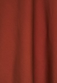 Tejido textil en color óxido profundo, textura suave, con sutiles variaciones en la tonalidad y caída ligera. Ideal para prendas o tapicería.