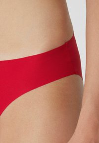 Rode bikini onderkant gemaakt van soepel, rekbaar materiaal, met een minimalistisch ontwerp en een hoge uitsnijding die de pasvorm en het comfort benadrukt.