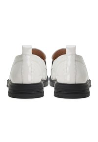 Paire de mocassins en cuir verni blanc avec semelles épaisses en caoutchouc noir, vus de dos sur fond blanc.