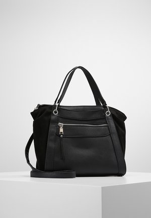 Mustan värinen keskikokoinen käsilaukku, jossa on kaksin käsikahvat, edessä vetoketjutasku ja pitkä säädettävä olkahihna, esillä valkoisella alustalla.