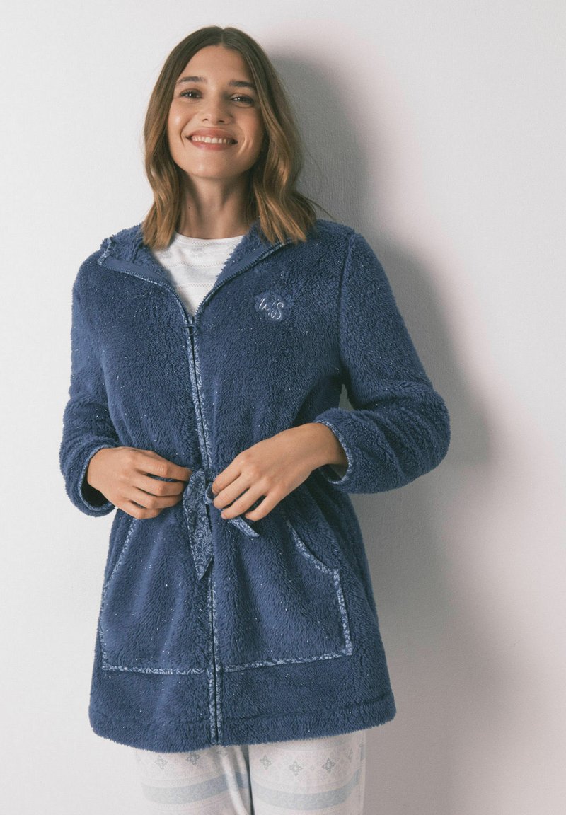 Marineblauwe fleece ochtendjas met een rits aan de voorkant, een capuchon en twee zakken. Heeft een gestructureerd oppervlak en een verstelbare taille met koord.