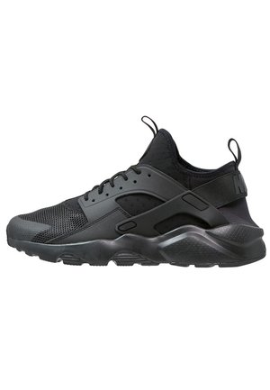 Baskets de sport noires avec embout en mesh, semelle épaisse et amortissante, fermeture à lacets à l’avant, et languette à l’arrière et sur la languette.