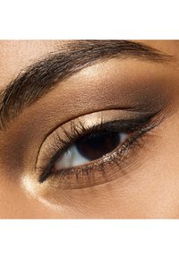 Close-up of a brown eye with subtle golden eyeshadow, defined eyeliner, and long lashes; smooth skin texture surrounding the eye.