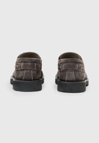 Scarpe in suede grigio con suole in gomma nera, caratterizzate da cuciture a contrasto e un design a profilo basso. La vista posteriore mostra una silhouette semplice e pulita.