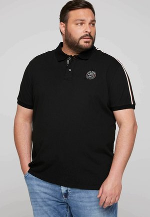 Zwarte polo met een kraag en een knoopsluiting met drie knopen. Heeft een ronde logopatch op de borst en contrasterende strepen op de mouwen.