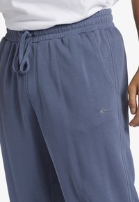 Marina blå sweatpants gjorda av mjukt tyg, med en elastisk midja med snörning, sidfickor och en liten logodetalj.