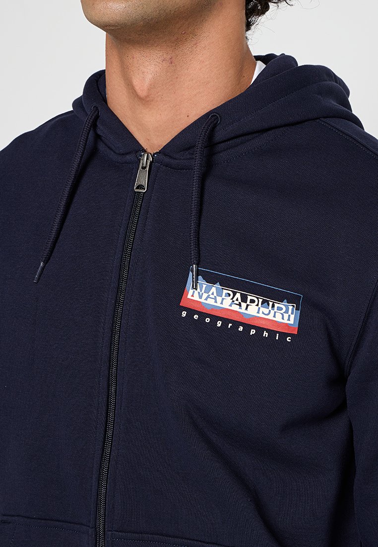 Marineblaue Zip-Hoodie aus einem Baumwollmischgewebe, mit einem Logo-Patch an der Vorderseite in Rot und Blau, Kängurutasche und Kapuze mit Kordelzug.