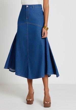 Jeans-Midirock mit ausgestellten Einsätzen, hoher Taille, vorderen Knopfdetails, kombiniert mit beigen Plateau-Peeptoe-Pumps und gestapelten goldenen Armspangen.