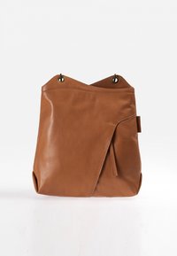 Braune Lederhandtasche mit weicher Textur, die ein einzigartiges Umschlag-Design, runde Metallakzente und ein Quasten-Detail an der Seite aufweist.
