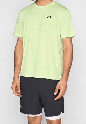 Mann trägt ein hellgrünes Under Armour Kurzarmshirt und schwarze Under Armour Shorts mit weißen inneren Kompressionsshorts.