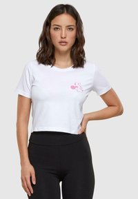 Witte katoenen cropped t-shirt met een roze afbeelding van een cartoon muis op de borst. Gladde textuur en korte mouwen. Zwarte legging inbegrepen.