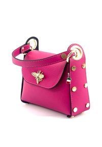Sac à main en cuir rose avec des accents dorés, un emblème d'abeille, des côtés cloutés et une courte poignée. Il dispose d'une fermeture à rabat et d'une surface texturée.