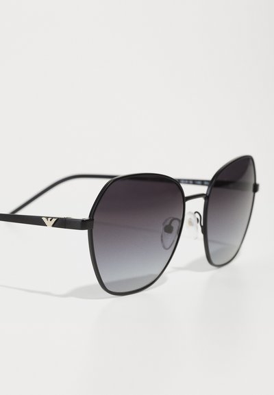 Ochelari de soare negri supra-dimensionați cu lentile întunecate în gradient, având rame subțiri din metal negru și accente aurii cu logo pe tâmple. Include pernuțe nazale transparente.