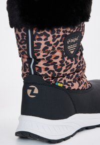Botte de neige noire et marron avec un upper en imprimé léopard, un col en fourrure noire pelucheuse, une étiquette imperméable, et une semelle blanche texturée.