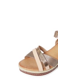 Sandalo con zeppa, con cinturini incrociati in bronzo metallico e una base morbida color beige. Presenta un motivo testurizzato, rifinitura in juta intrecciata e una suola in gomma bianca.