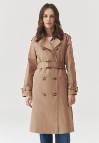 Beiger Trenchcoat mit Doppelreiher-Design, großen Knöpfen, Taillengürtel und Schulterklappen. Verfügt über lange Ärmel und Seitentaschen.