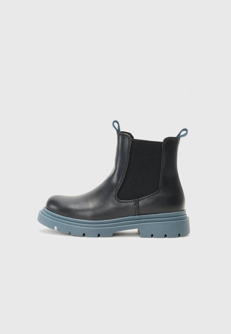 Botas de couro pretas até ao tornozelo com sola de borracha azul, painéis laterais elásticos e puxadores traseiros. Bico arredondado e salto grosso para maior estabilidade.