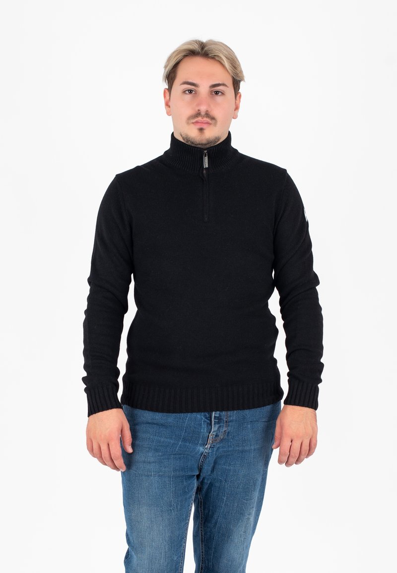 Maglione nero lavorato a maglia con colletto alto e design con zip a metà. Polsini e orlo a costine. Abbinato a jeans in denim blu.