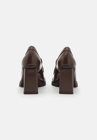 Chaussures en cuir verni marron avec un bout carré, une semelle texturée et des talons blocs larges. Présentent des accents de couture sur la partie supérieure.