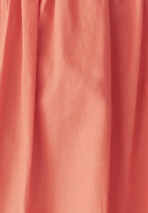 Persiku krāsas audums ar gludu faktūru, kuram ir maigi savilktas drapērijas, kas veido plūstošu izskatu.