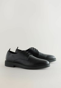 Mustad mustadest nahast kingad sileda viimistlusega, ümarates varvastega ning minimalistikus disainis; sisaldavad paelu ja madala profiiliga kummist tallat.