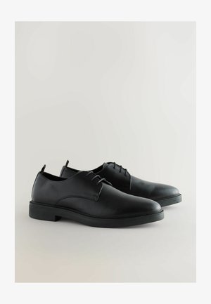 Black leather dress shoes with a smooth finish, rounded toe, and minimalistic design; features laces and a low-profile rubber sole.