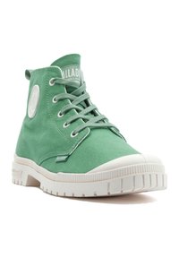 Grüne Canvas-Ankle-Boots mit weißen Gummi-Sohlen, versehen mit rundem Logo-Patch, Schnürung und seitlichen Stickdetails.