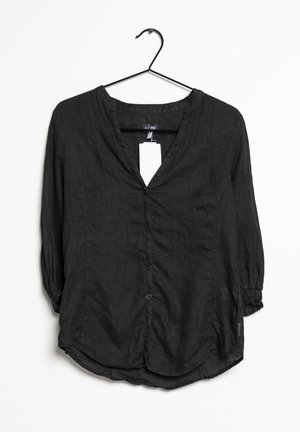 Zwarte blouse met knopen, lange mouwen, een V-hals en een afgeronde zoom, hangend aan een zwarte hanger tegen een witte achtergrond.